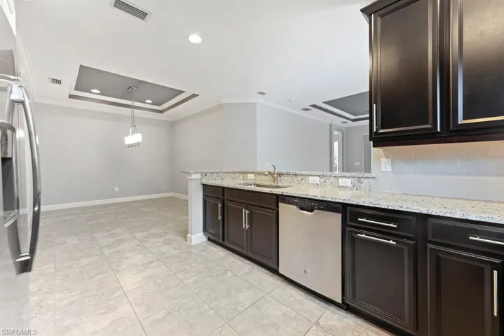Kitchen with ornamental molding, a raised ceiling, backsplash, and stainless steel appliances