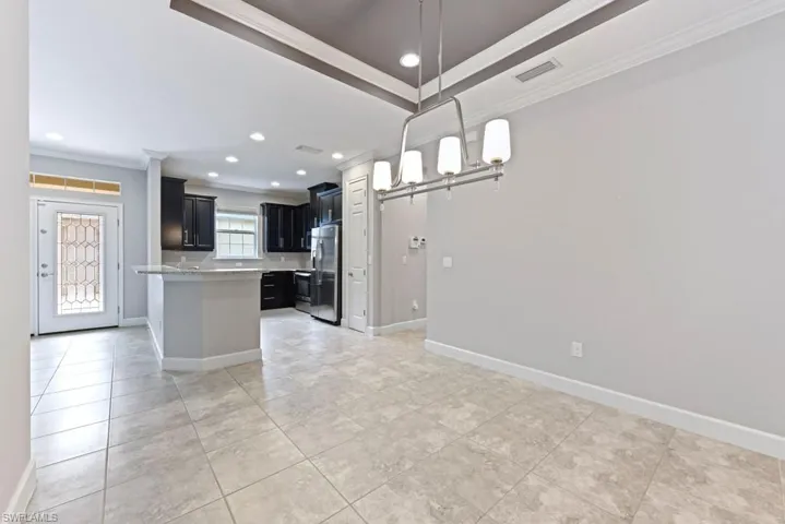 Kitchen with decorative light fixtures, stainless steel refrigerator, and ornamental molding