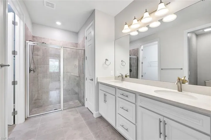 Bathroom featuring tile patterned flooring, vanity, toilet, and an enclosed shower