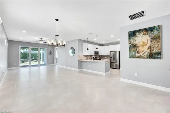 Unfurnished living room with ceiling fan with notable chandelier and light tile patterned floors
