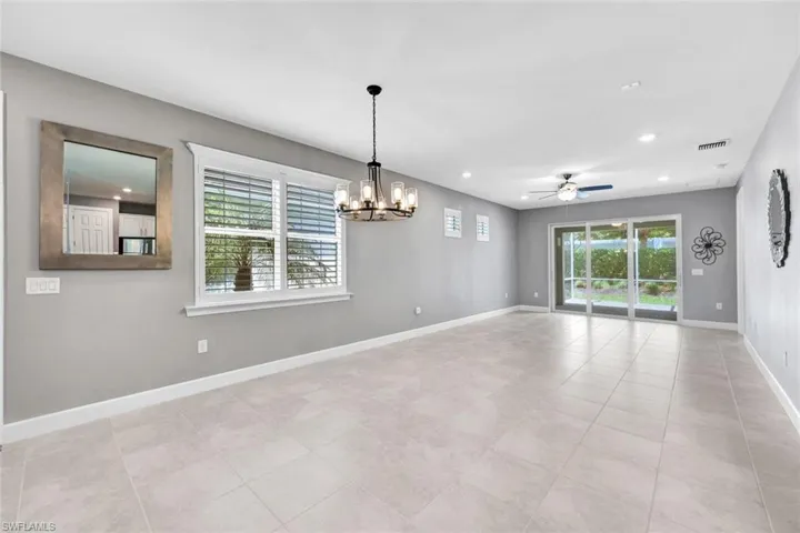 Tiled empty room with ceiling fan with notable chandelier