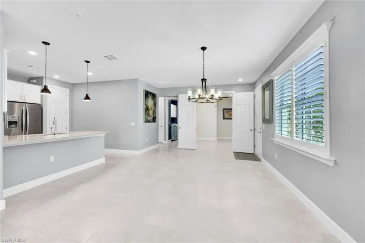 Unfurnished living room with a chandelier, light tile patterned flooring, and sink