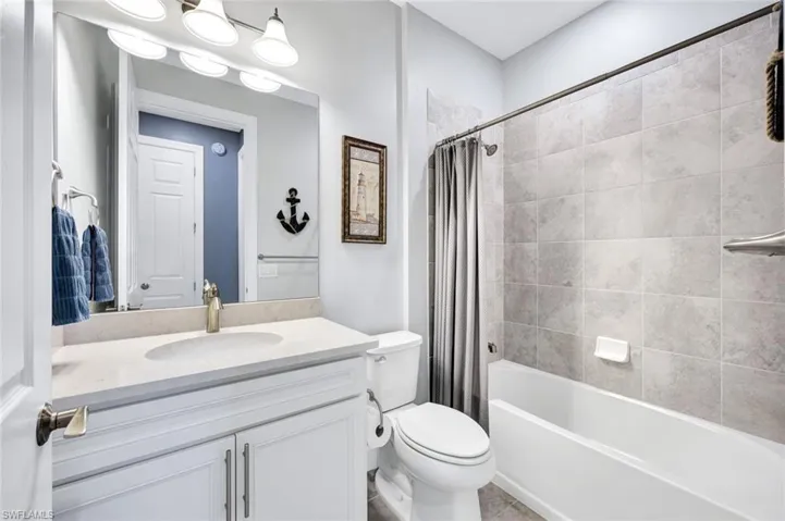 Full bathroom featuring vanity, toilet, shower / bath combination with curtain, and tile patterned flooring