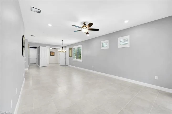 Unfurnished room with ceiling fan with notable chandelier