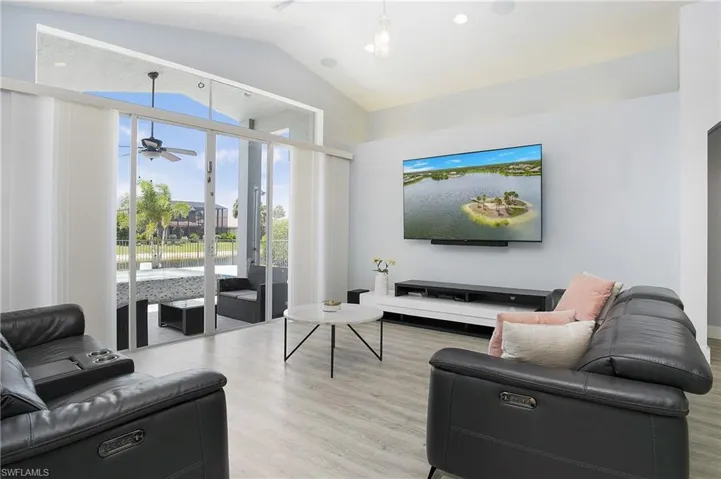 Living room featuring light hardwood / wood-style floors, vaulted ceiling, and ceiling fan