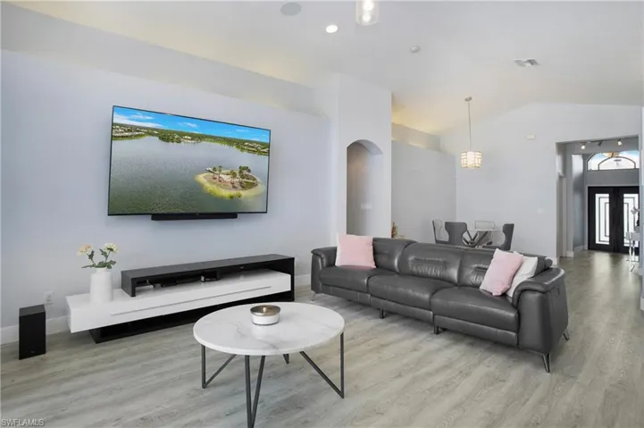 Living room with light hardwood / wood-style flooring and vaulted ceiling
