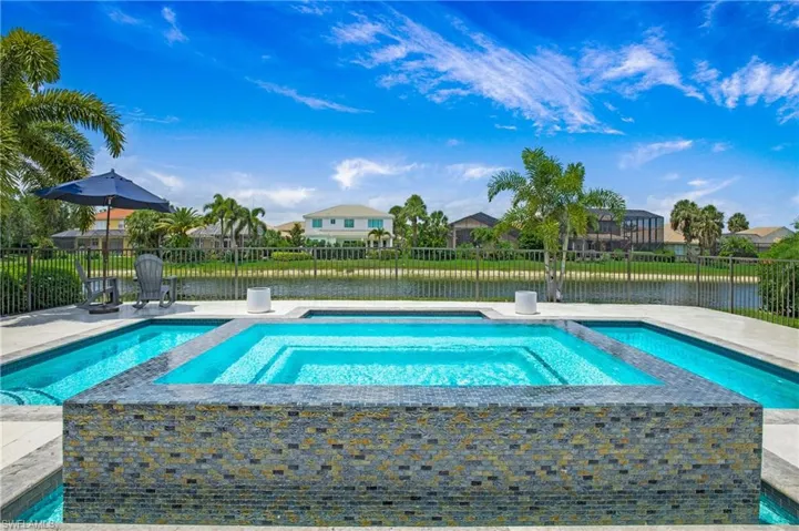 View of swimming pool with an in ground hot tub and a water view