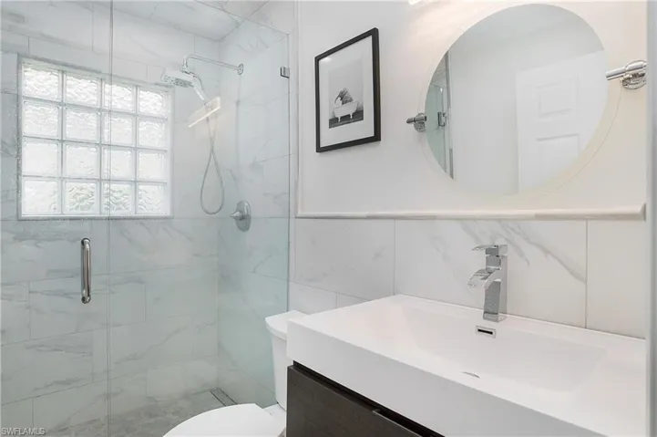Bathroom featuring vanity, toilet, tile walls, tasteful backsplash, and a shower with shower door
