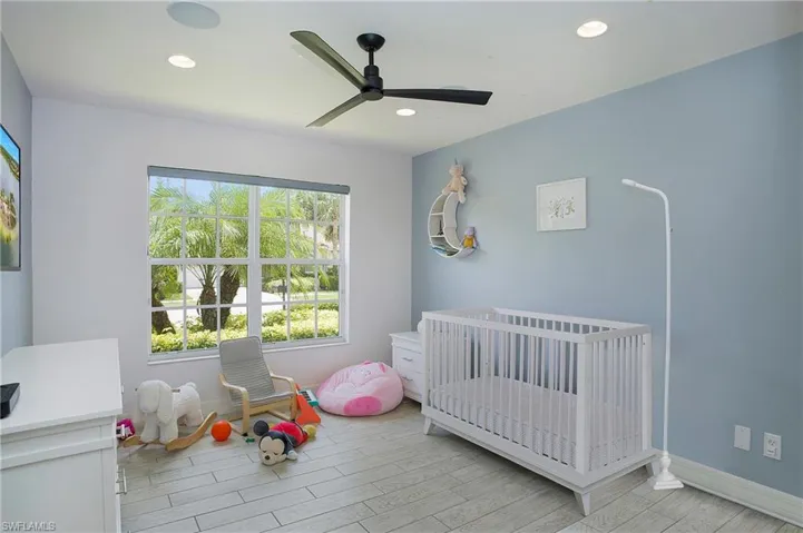 Bedroom featuring a nursery area and ceiling fan