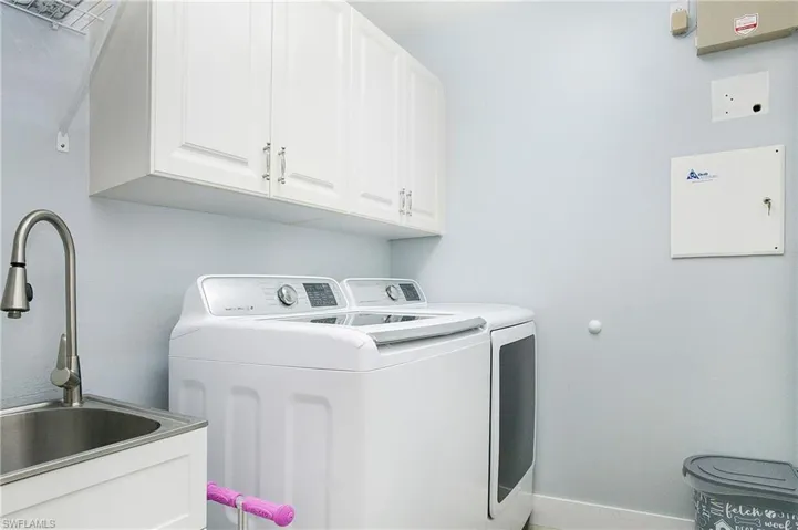 Washroom with washing machine and dryer, sink, and cabinets