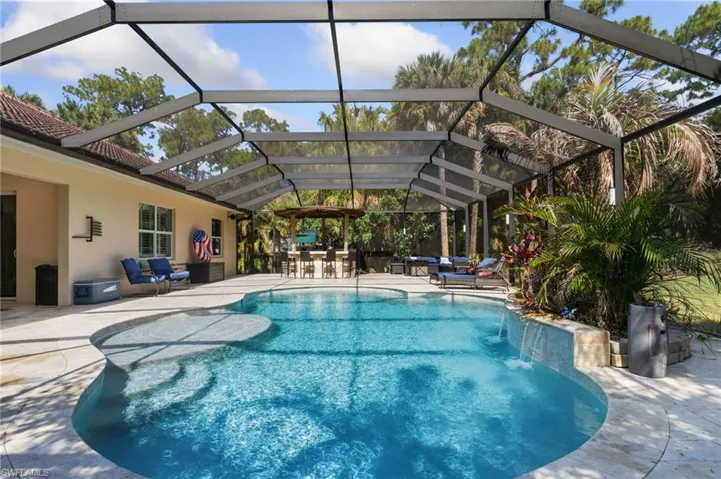 Custom pool featuring water fall and sun shelf, screened lanai with bar and outdoor kitchen.