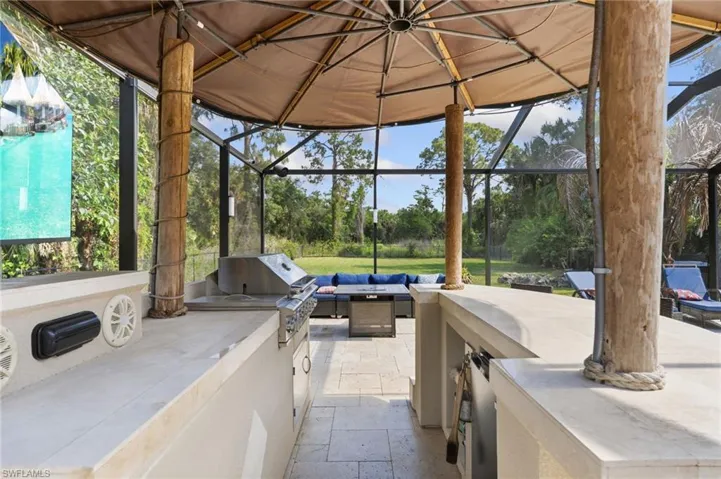 Tiki bar with outdoor kitchen, surround sound speakers throughout the lanai area.