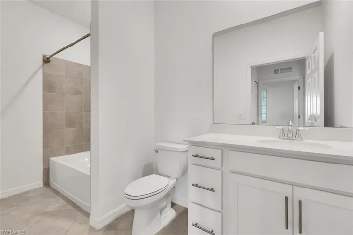 White vanity with brushed nickel hardware, light-toned countertop, and undermount sink with a chrome faucet