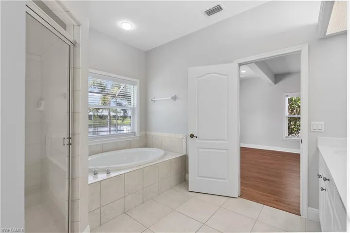 Full bathroom with a bath, tile patterned flooring, vanity, a shower stall, and plenty of natural light