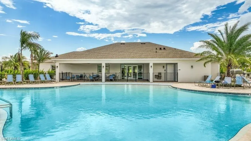 The property features an expansive outdoor pool with a surrounding paved deck, complete with lounge chairs for relaxation