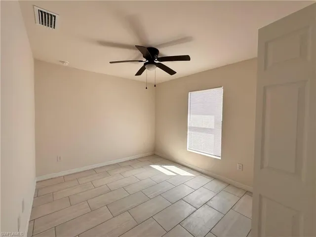 Empty room featuring baseboards, visible vents, and ceiling fan