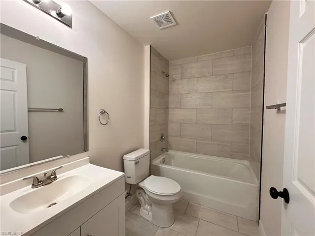 Bathroom with vanity, visible vents, tile patterned flooring, shower / bathing tub combination, and toilet