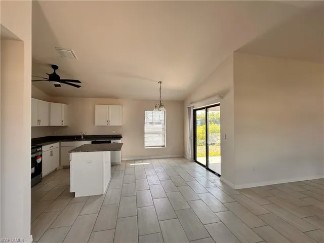 Kitchen with visible vents, a kitchen island, dark countertops, white cabinets, and hanging light fixtures