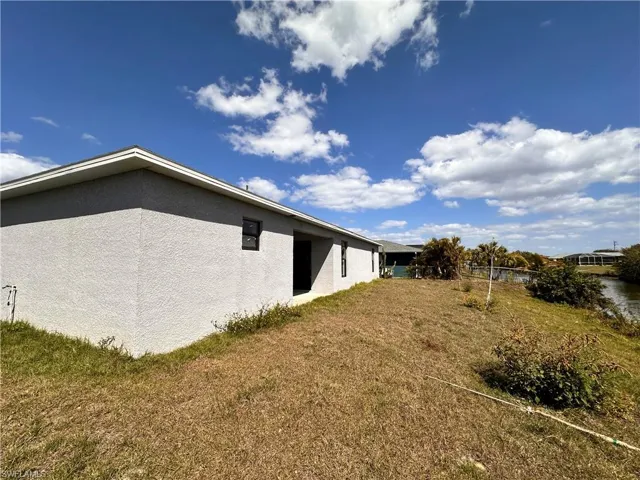 View of side of home with a lawn and stucco siding
