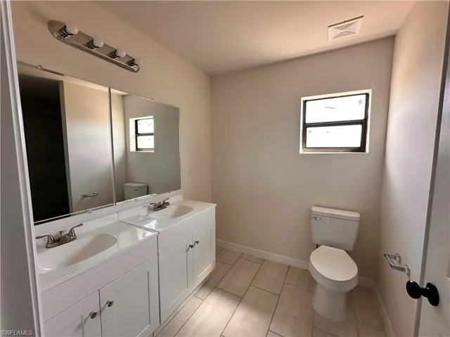 Bathroom featuring a sink, visible vents, baseboards, and toilet