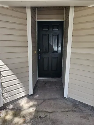 Entryway featuring a paneled door, horizontal siding, and a concrete landing
