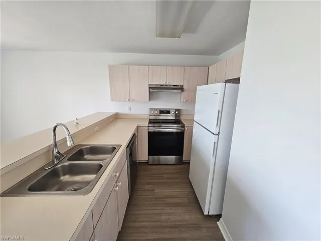Kitchen featuring light-toned cabinetry, laminate countertops, and wood-finish flooring