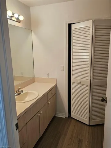 Bathroom featuring a wood-finish vanity with a light-toned countertop, an integrated sink, and a large wall-mounted mirror
