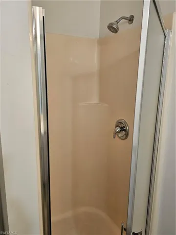 Enclosed shower stall featuring a composite surround, brushed nickel showerhead, and a coordinating single-handle valve