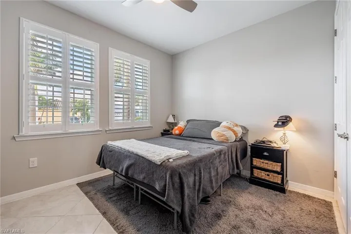 Tiled bedroom featuring ceiling fan