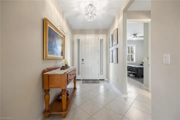 Foyer featuring light tile patterned flooring and ceiling fan with notable chandelier