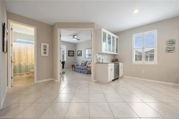 Kitchen featuring tasteful backsplash, wine cooler, ceiling fan, and white cabinets