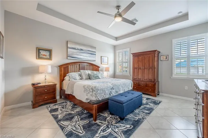 Tiled bedroom with a tray ceiling and ceiling fan