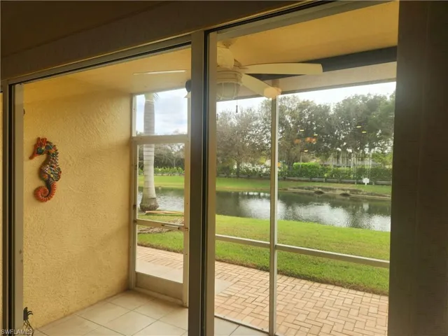 Doorway featuring light tile patterned flooring, a water view, and ceiling fan