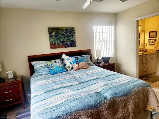 Bedroom featuring ensuite bath, light hardwood / wood-style flooring, and ceiling fan