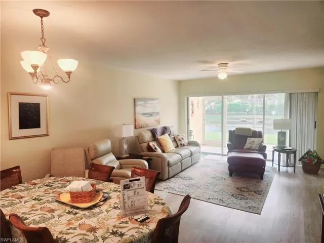 Living room with wood-type flooring and ceiling fan with notable chandelier