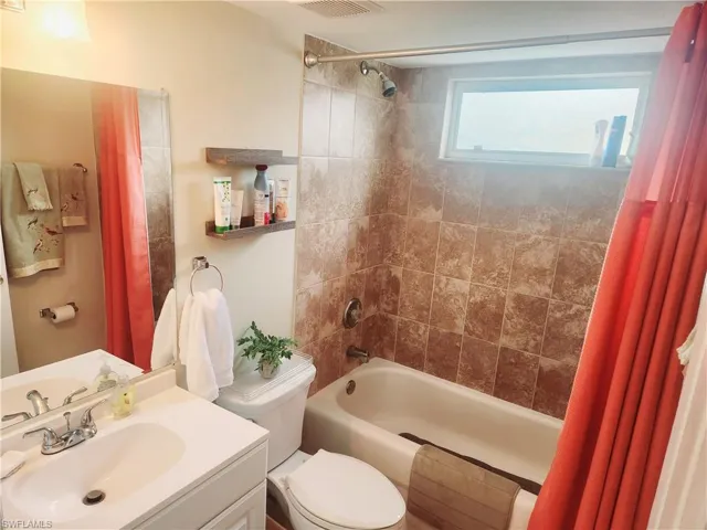 Full bathroom featuring vanity, shower / bath combo, and toilet