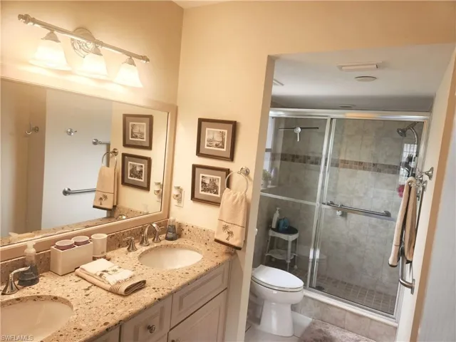 Bathroom featuring vanity, tile patterned floors, toilet, and an enclosed shower