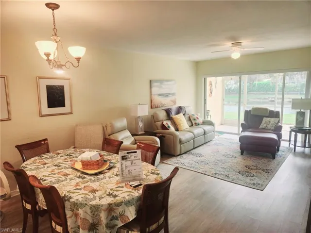 Dining space with wood-type flooring and ceiling fan with notable chandelier