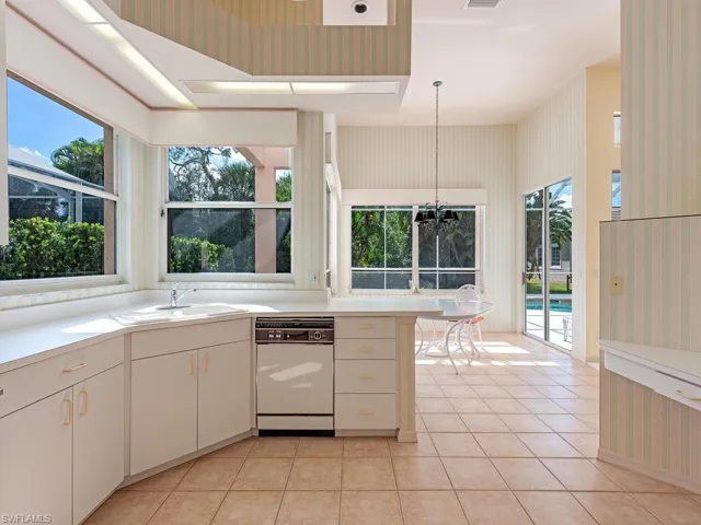 Kitchen featuring a wealth of natural light, white dishwasher, light tile patterned floors, and hanging light fixtures