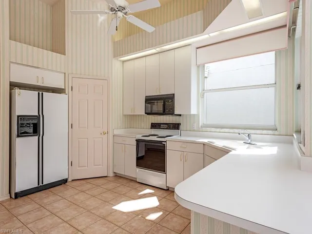 Kitchen featuring ceiling fan, sink, light tile patterned floors, white appliances, and white cabinets
