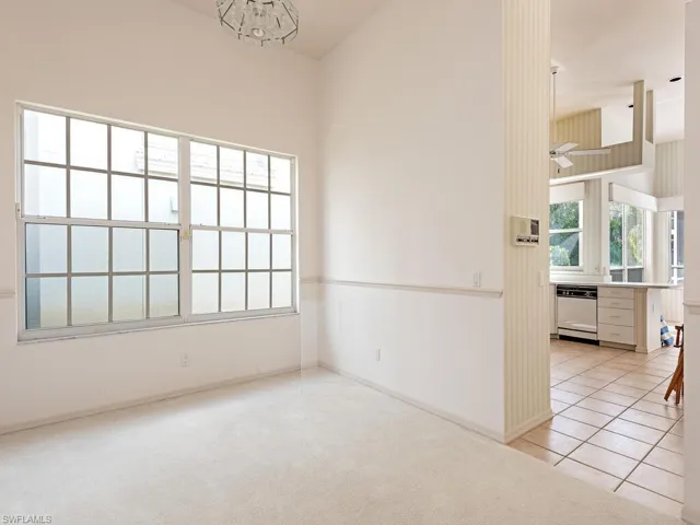 Carpeted spare room with plenty of natural light and a towering ceiling