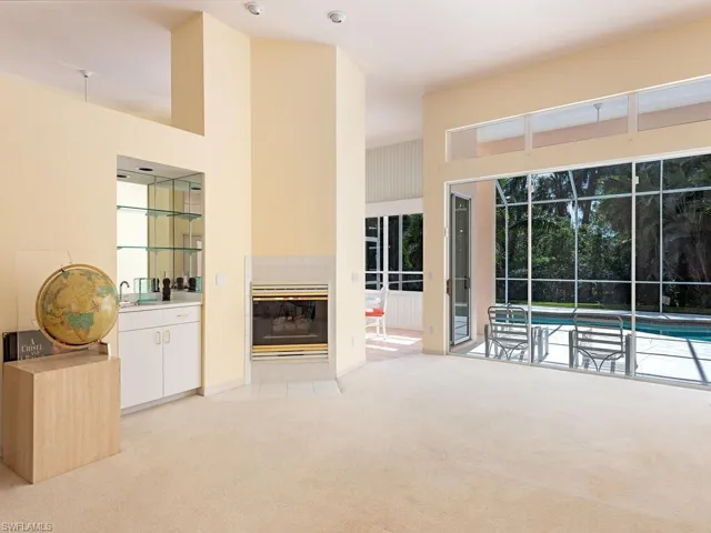 Unfurnished living room with a tile fireplace, light carpet, sink, and a high ceiling