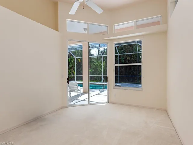 Empty room featuring ceiling fan, light carpet, and a high ceiling