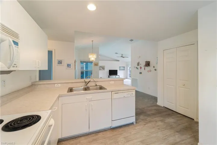 Kitchen featuring sink, light hardwood / wood-style floors, white appliances, and pendant lighting