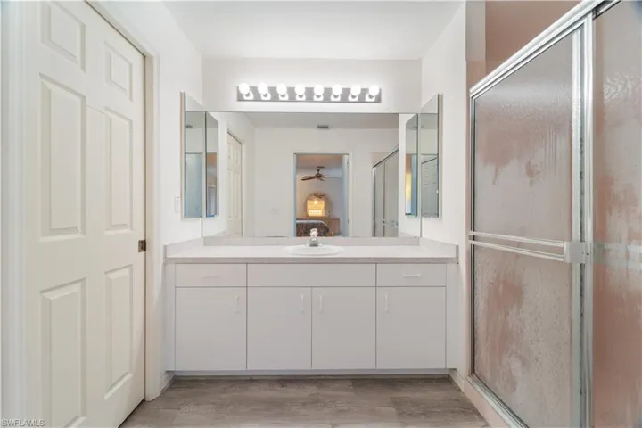 Bathroom with a shower with shower door, ceiling fan, vanity, and hardwood / wood-style flooring
