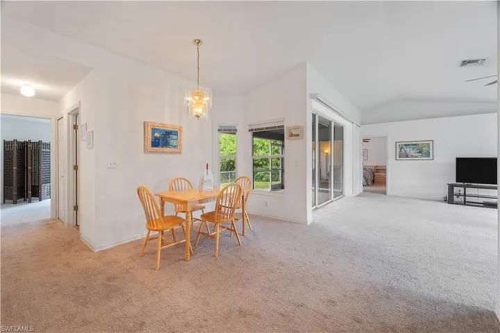 Carpeted dining area featuring a notable chandelier and lofted ceiling