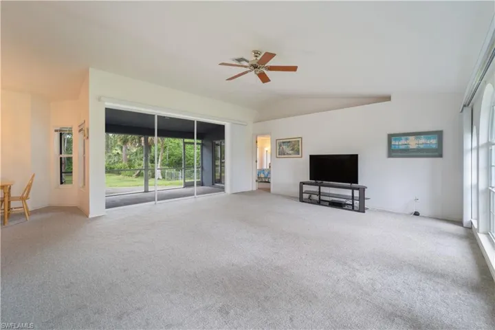 Unfurnished living room with ceiling fan, carpet floors, and vaulted ceiling