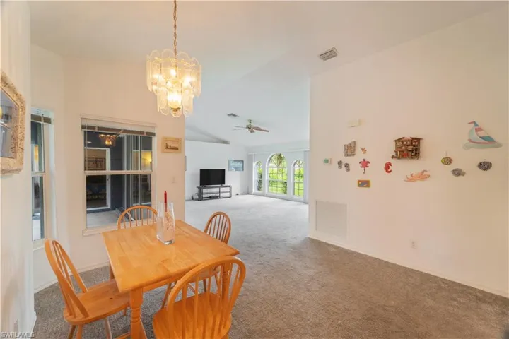 Dining room with high vaulted ceiling, carpet floors, and ceiling fan with notable chandelier