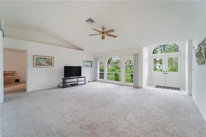 Unfurnished living room featuring carpet flooring, high vaulted ceiling, ceiling fan, and french doors