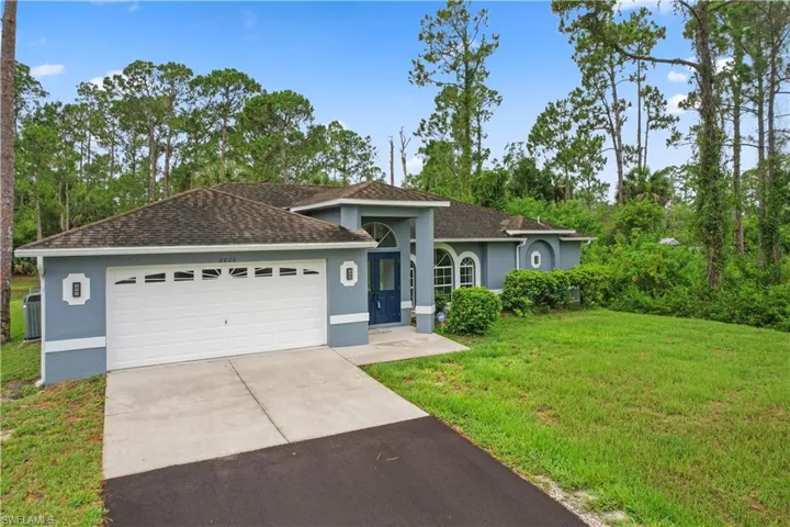 Single story home featuring a garage and a front lawn